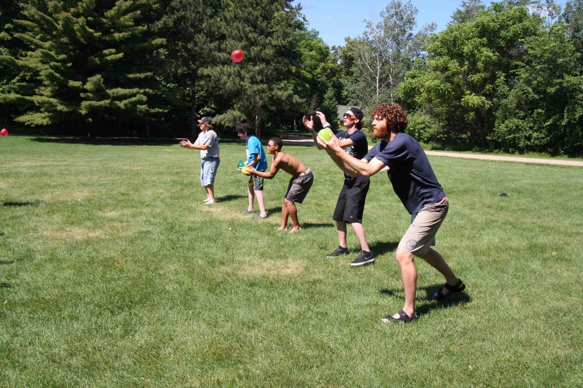 Campers playing ball in the grass.