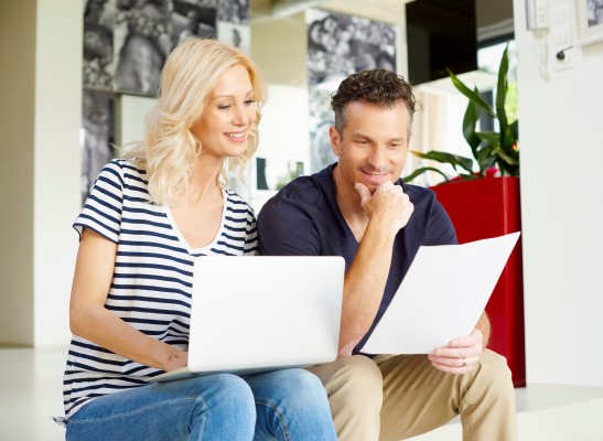Woman with computer on her lap and man next to her looking at documents together