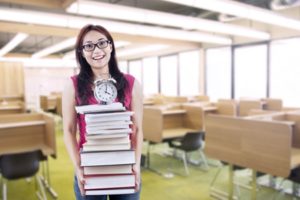 Young woman carrying a tall stack of books