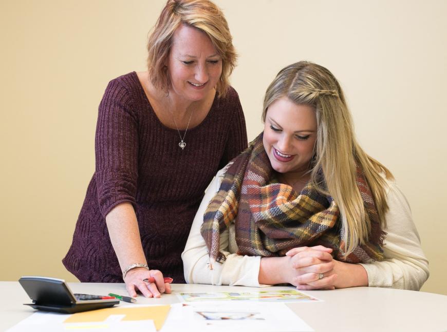 Two women reviewing documents and smiling