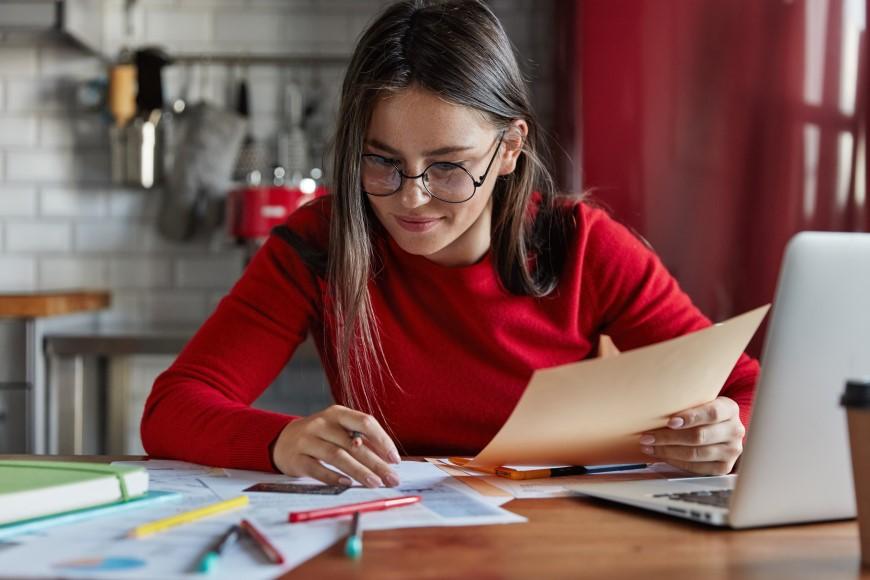 Woman working at desk with laptop and paperwork