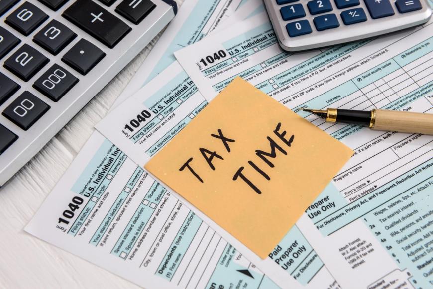 Post-It note saying Tax Time and laying on top of federal tax forms