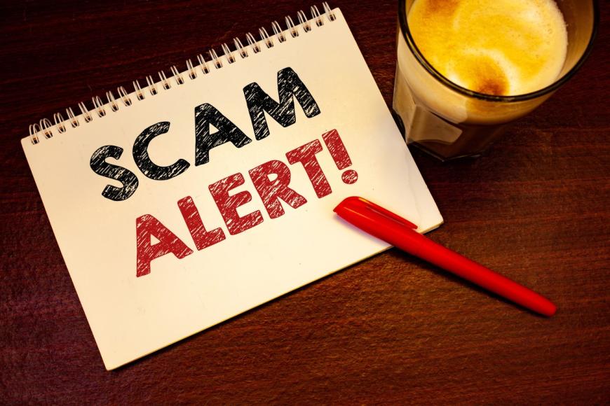 SCAM ALERT written on cover of three-ring notebook
