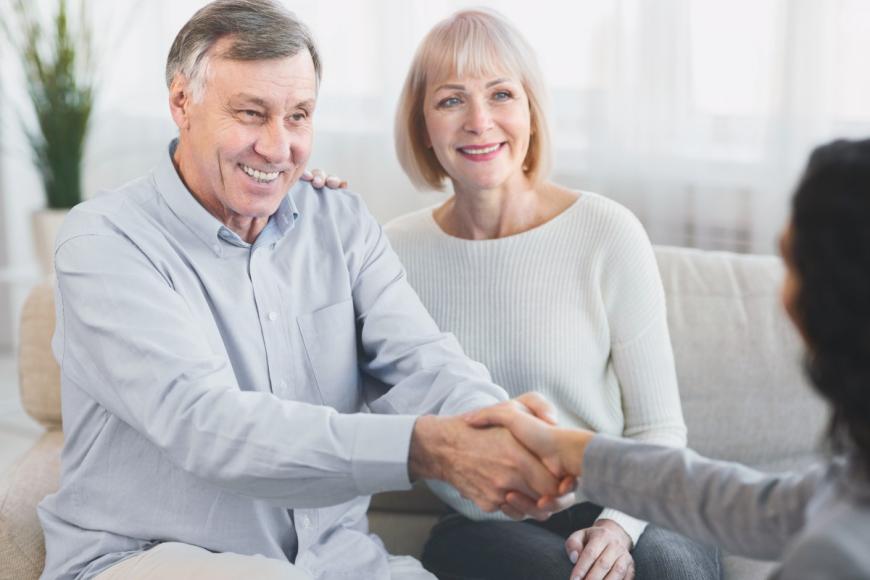 Older man with older woman, shaking hands with mental health care provider