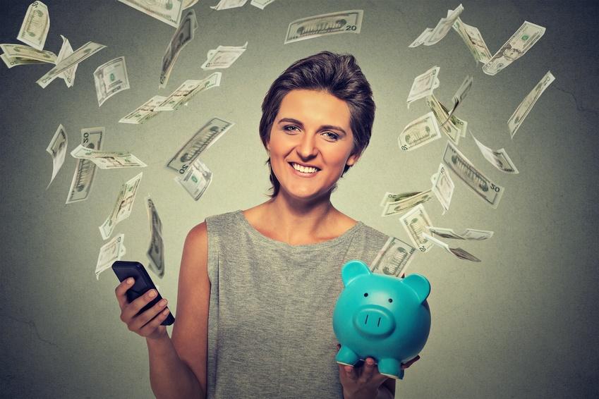 Women holding piggy bank and being showeed by dollar bills