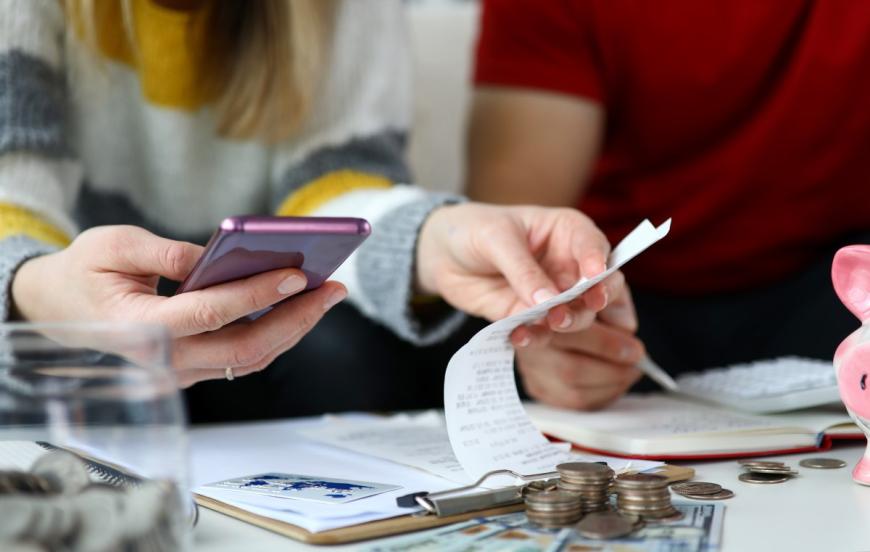 Woman looking at receipts with cell phone in one hand