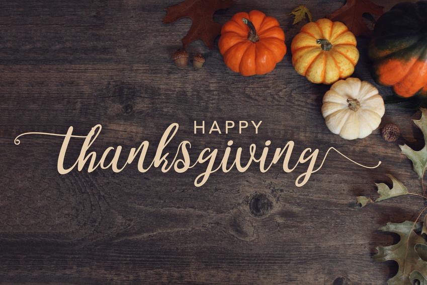 Happy Thanksgiving text overlaid on brown background with pumpkins
