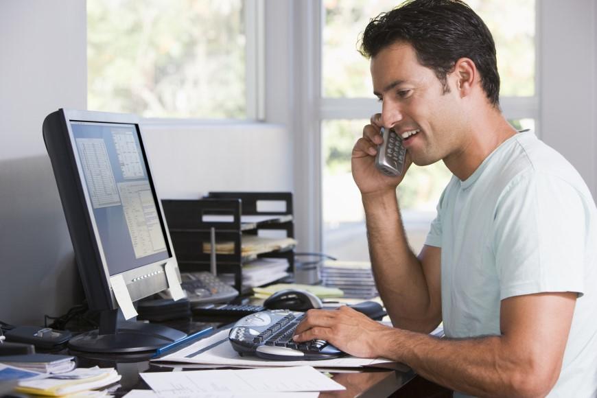 Man looking at laptop screen and talking on cell phone