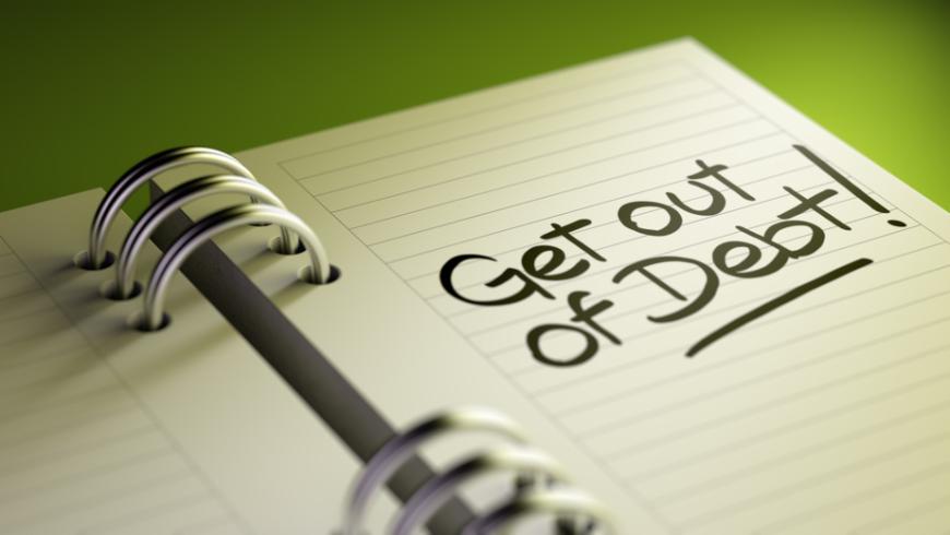 Open spiral notebook with words "{Get out of debt" written on right page