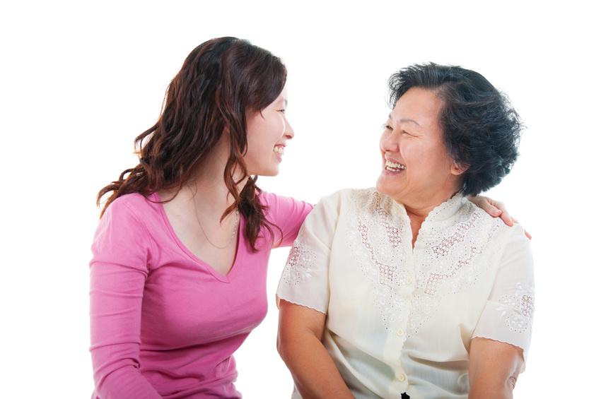 Young adult with arm around older adult. The two are smiling at each other