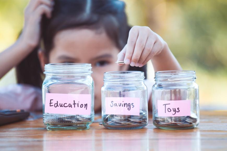 Little girl putting change in to three jars