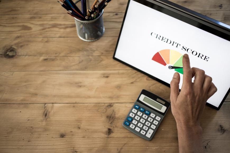 Hand reaching toward computer screen that has graphic of high credit score