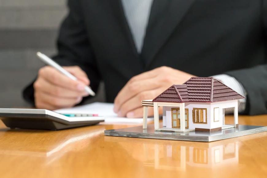 Woman's hands with calculator and house