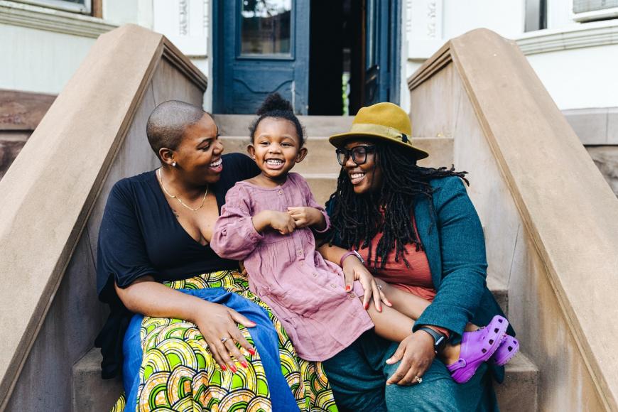 two african american women sitting on steps with their daughter
