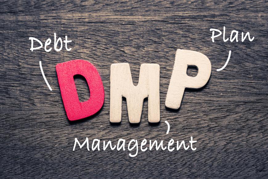 Letters DMP overlaid on a wooden surface. Next to the “D” is the word Debt, next to the “M” is the word Management, and next to the “P” is the word Plan.
