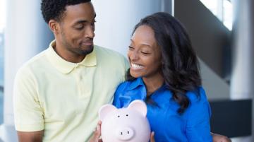 Young African-American couple holding piggy bank and smiling