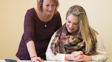 Two women reviewing documents and smiling