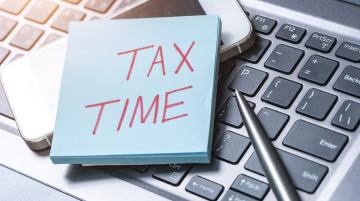 Post it note on calculator that says "Tax Time"