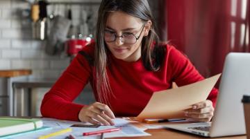 Woman working at desk with laptop and paperwork