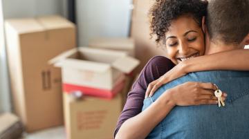 Woman holding keys to new house and hugging partner