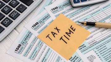 Post-It note saying Tax Time and laying on top of federal tax forms