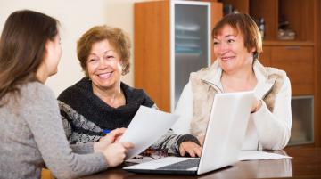 Couple smiling while discussing paper with woman