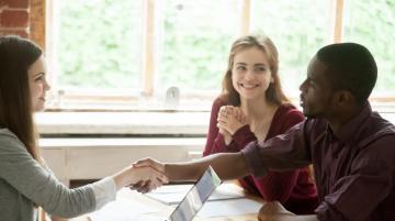 Young man and young woman meeting with other woman; young man shakes hand of other woman