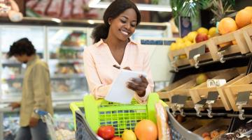 Young Black woman shopping for groceries and comparing grocery prices