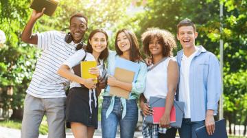 Multiracial group of five college students with their arms around each other and smiling for the camera
