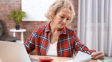 Woman looking at papers and working at laptop