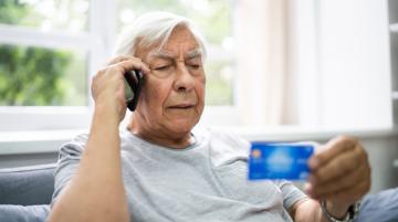 Older man on cell phone holding credit card