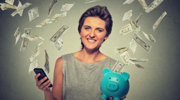 Women holding piggy bank and being showeed by dollar bills