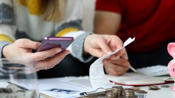 Woman looking at receipts with cell phone in one hand