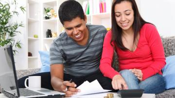 Young Hispanic/Latinx couple looking at financial papers and using a calculator