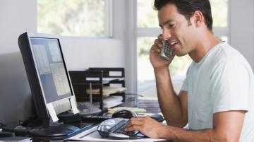 Man looking at laptop screen and talking on cell phone