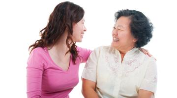 Young adult with arm around older adult.  The two are smiling at each other