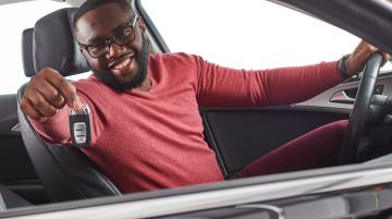 Man sitting in driver's seat of car and showing car keys