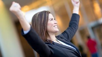 Woman in celebratory pose -- arms raised and fists clienched
