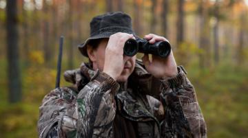 Man holding binoculars in the woods