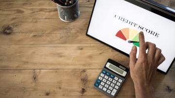 Hand reaching toward computer screen that has graphic of high credit score