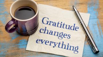 Words on post it note: Gratitude Chnages Everything.  Cup of coffee and pen next to post-it note.