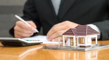 Woman's hands with calculator and house