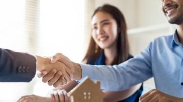 Asian woman and man meeting realtor. Man shaking realtor's hand.