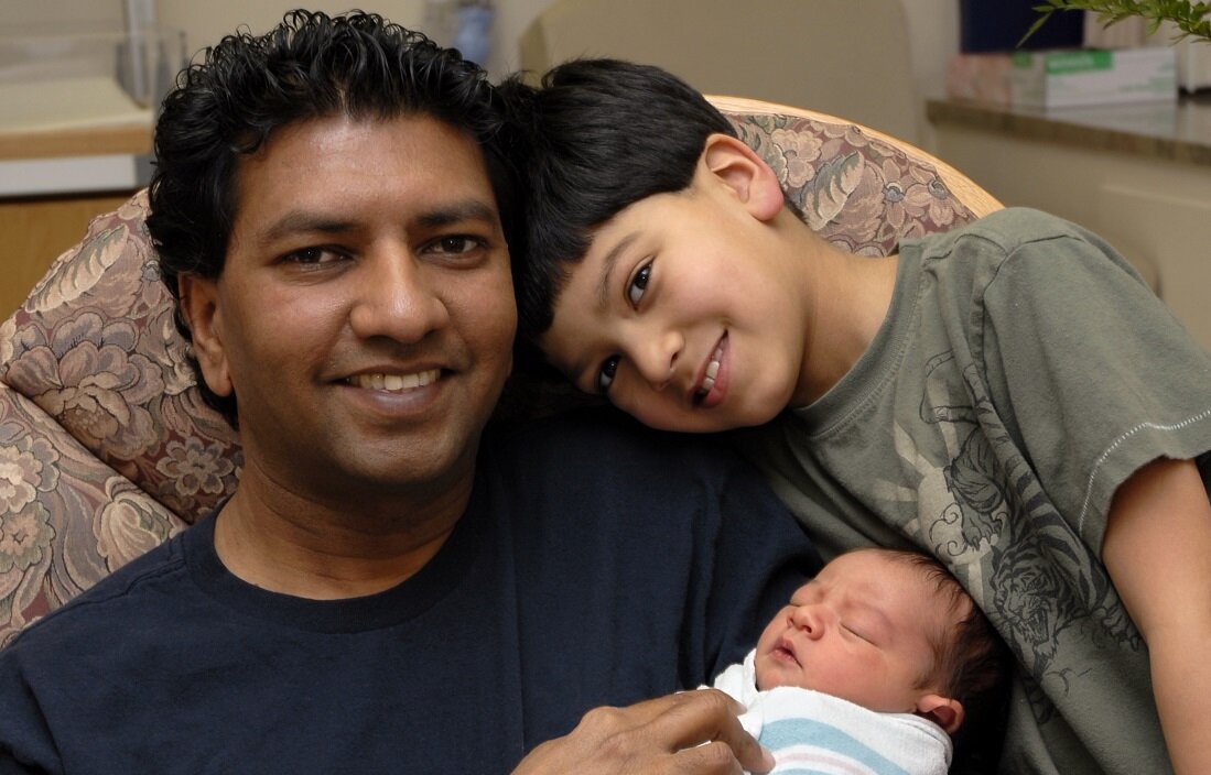 Man with a young child, holding a new born child.