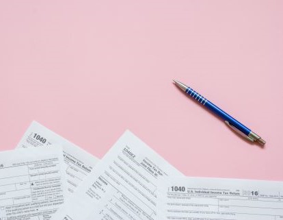 2024 Tax Filing Documents on a pink background by a blue pen