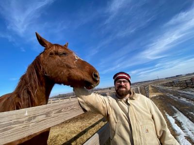 John on a farm petting a horse.
