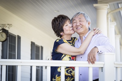Married couple hugging on porch.