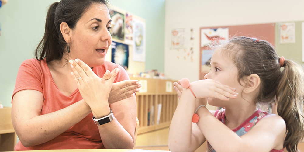 Woman and little girl signing together at a classroom table