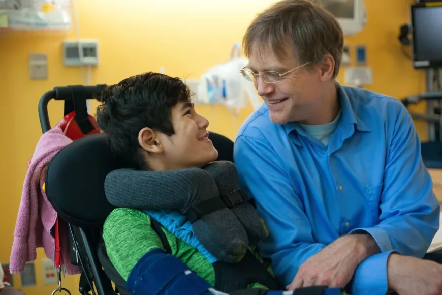 Young boy in a wheelchair by adults side