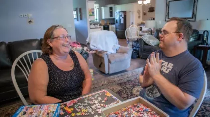 Joann and Zach solving a puzzle together on a dinner table